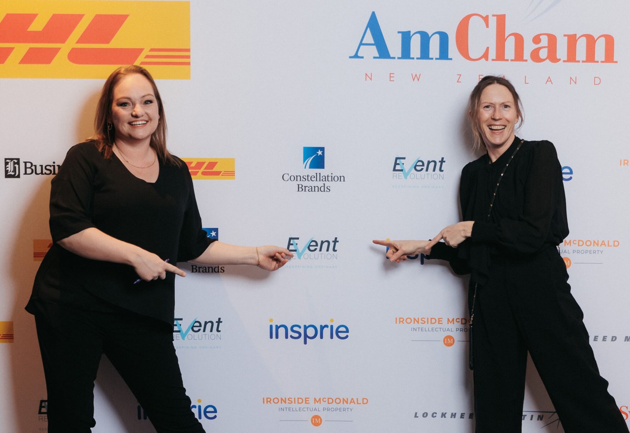Deb and Karla standing in front of the sponsor board